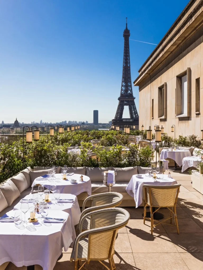 Terrace banquette and tables with the Eiffel Tower and Paris skyline beyond at Girafe Paris