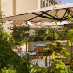 Terrace tables framed by lush planting and parasols beside the Palais at Girafe Paris