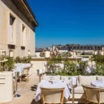 Rooftop terrace with an outdoor bar and set tables over the Paris rooftops at Girafe Paris