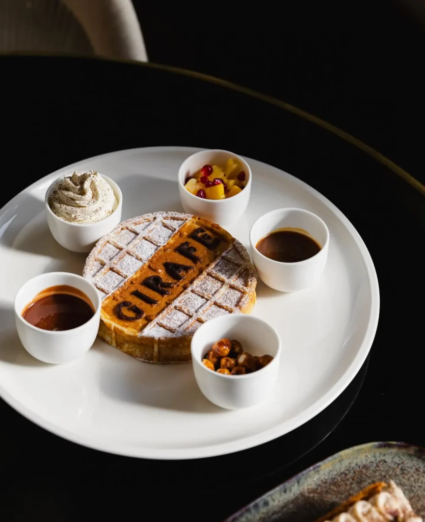 Waffle branded GIRAFE with cream and dipping sauces on a white plate at Girafe Paris