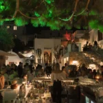 Busy central bar beneath a green-lit pine at night at Interni Restaurant Mykonos