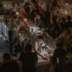 Bartenders mixing drinks behind the bar as guests gather at night at Interni Restaurant Mykonos