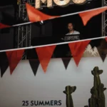 DJ playing beneath an illuminated MOS sign framed by bunting at Interni Restaurant Mykonos