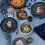 Spread of pasta, seared tuna, salmon and grain bowls on a marble surface at Interni Restaurant Mykonos
