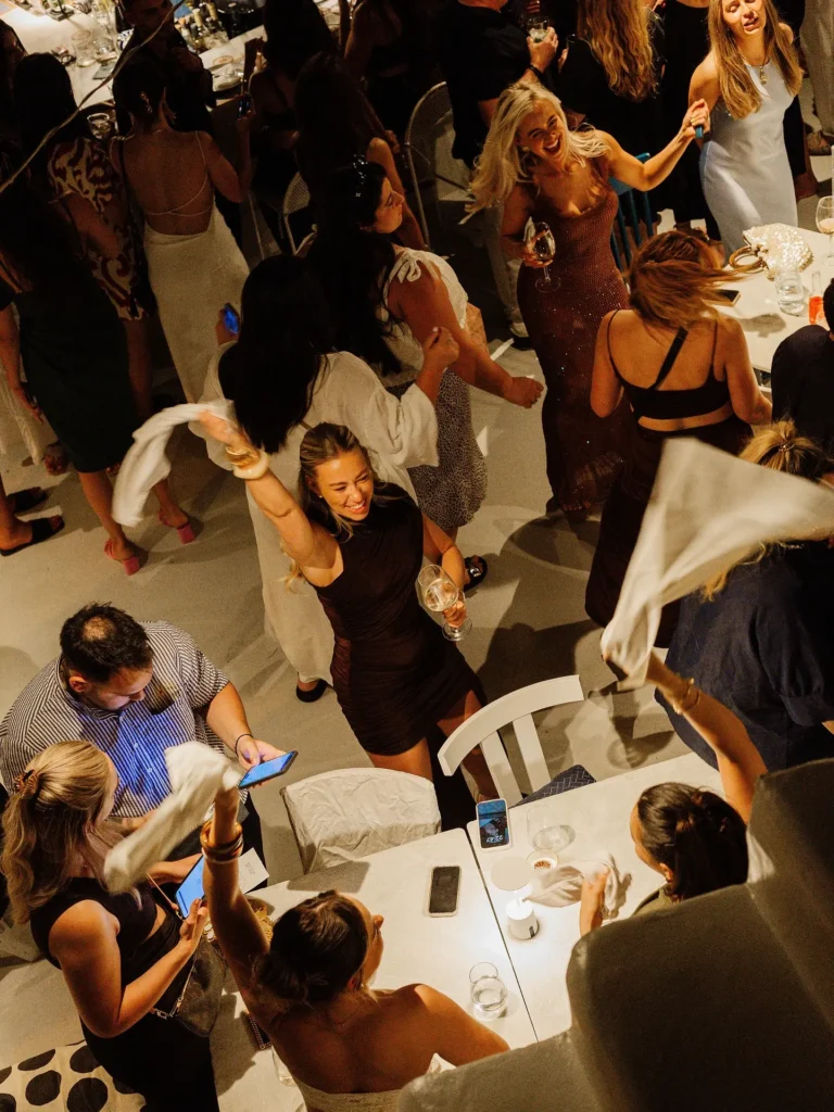 Guests dancing with napkins overhead between the tables at Interni Restaurant Mykonos