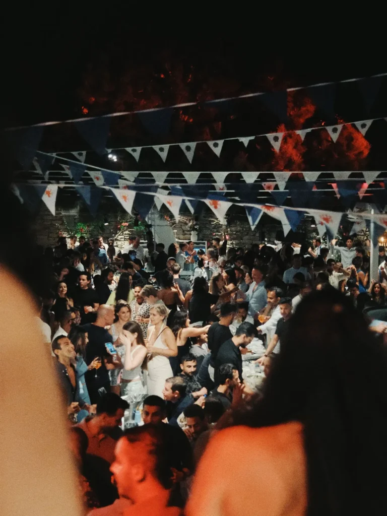 Dense party crowd beneath blue-and-white bunting at night at Interni Restaurant Mykonos