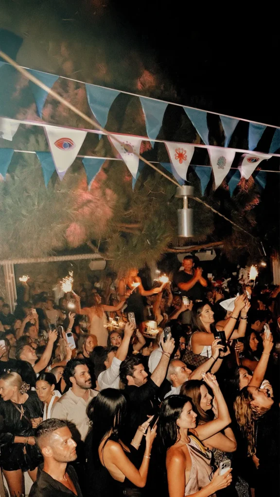 Guests celebrating with sparklers under evil-eye bunting at night at Interni Restaurant Mykonos