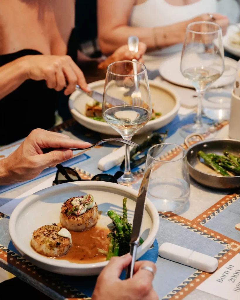 Seared scallops in sauce with broccolini as guests dine at Interni Restaurant Mykonos