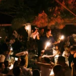 Waiter holding sparklers aloft at the bar amid a cheering crowd at Interni Restaurant Mykonos