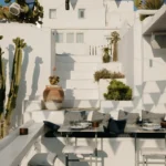 Cushioned corner banquette and high tables among cacti and whitewashed steps at Interni Restaurant Mykonos