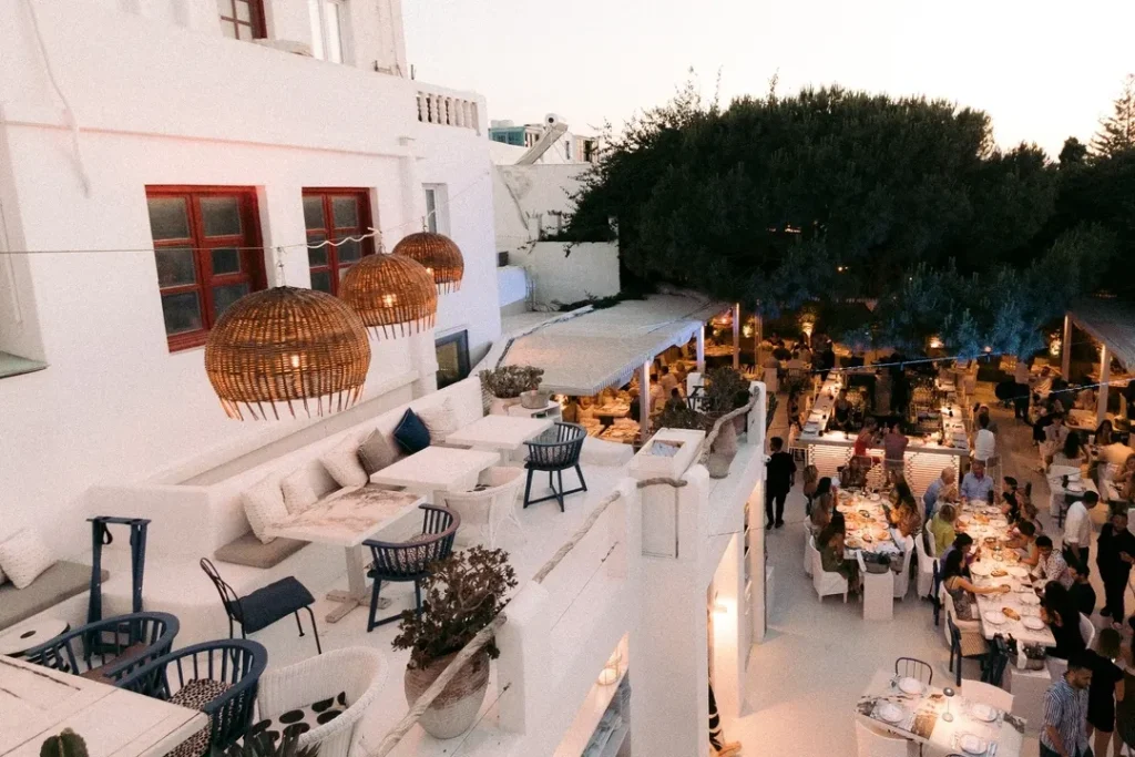 White terraces with rattan pendant lights and set tables at twilight at Interni Restaurant Mykonos