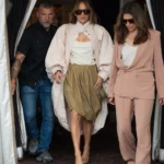 Jennifer Lopez in a pink coat and olive skirt leaving the entrance at lavenue Paris
