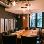 Private dining table under globe pendants beside framed VINOS prints and exposed brick at La Bodeguilla Palma