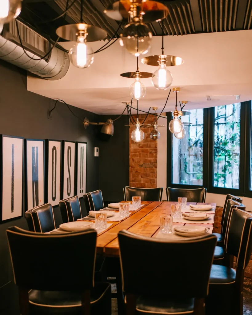 Private dining table under globe pendants beside framed VINOS prints and exposed brick at La Bodeguilla Palma