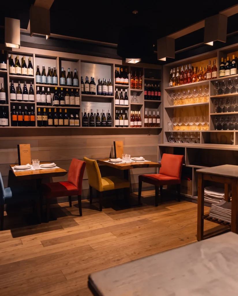 Set tables with red and yellow chairs before a shelved wine wall at La Bodeguilla Palma