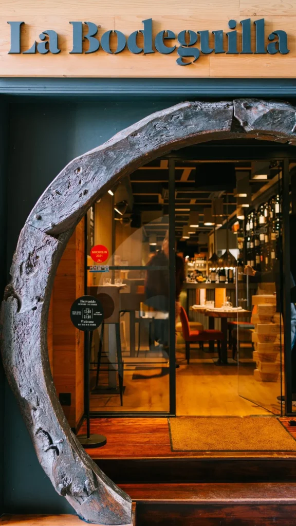 Barrel-ring arch entrance with a Michelin sticker looking into the wine-lined interior at La Bodeguilla Palma