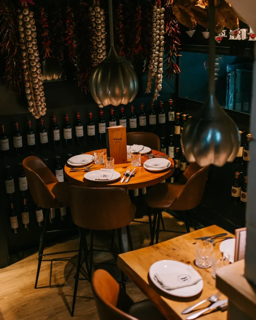 High table below strings of garlic and dried chillies against a wall of wine bottles at La Bodeguilla Palma