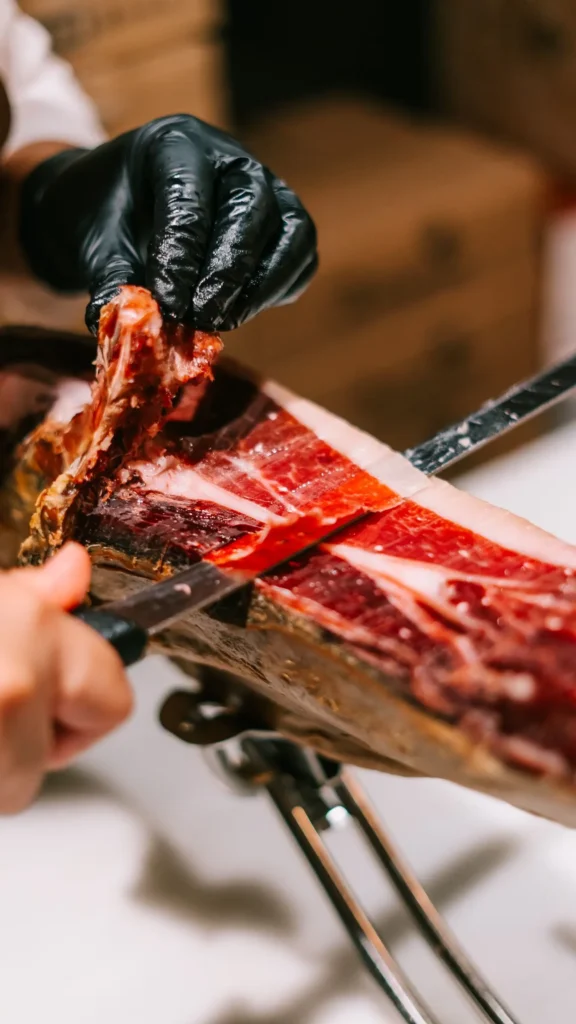 Gloved hand carving thin slices from a leg of Iberian jamón at La Bodeguilla Palma