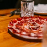 Plate of thinly sliced Iberian jamón on a wooden table at La Bodeguilla Palma