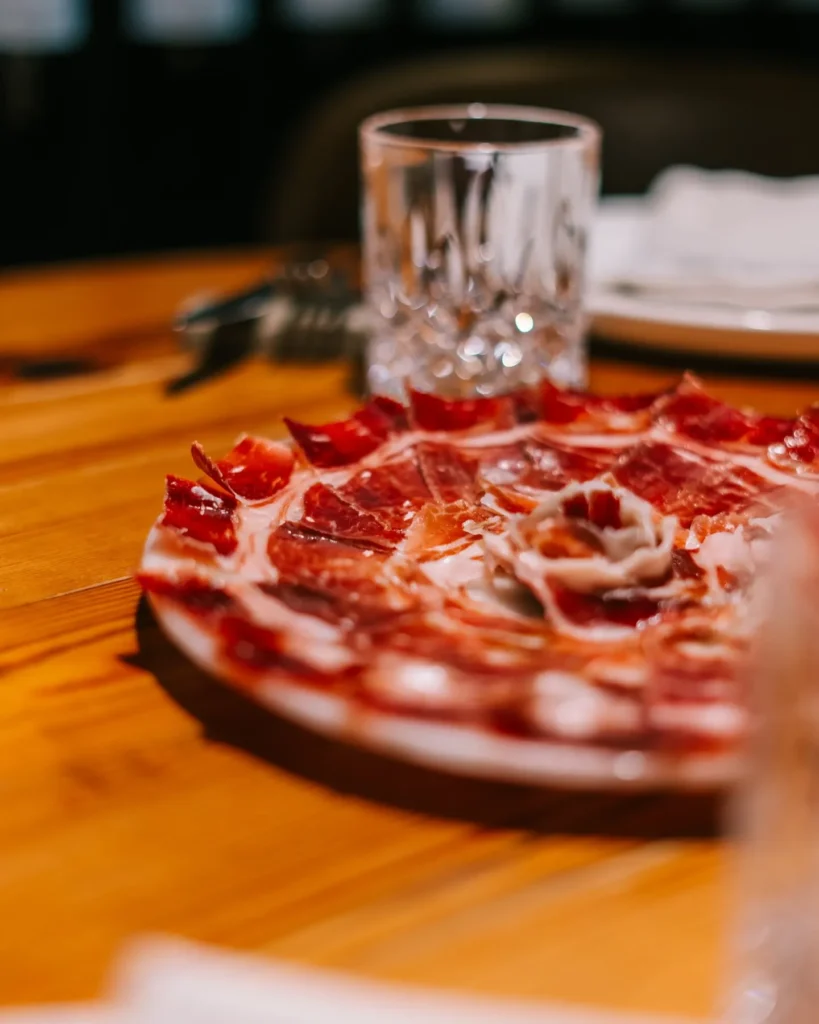 Plate of thinly sliced Iberian jamón on a wooden table at La Bodeguilla Palma
