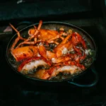 Lobster pieces cooking in a pan over glowing coals at La Bodeguilla Palma