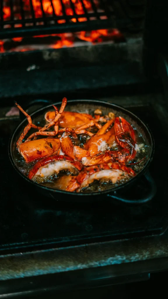 Lobster pieces cooking in a pan over glowing coals at La Bodeguilla Palma
