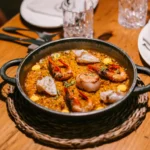 Pan of seafood rice with prawns, scallop and fish in an iron pan at La Bodeguilla Palma