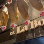 La Bodeguilla lettering below rows of hanging cured jamón at La Bodeguilla Palma
