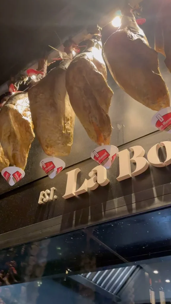 La Bodeguilla lettering below rows of hanging cured jamón at La Bodeguilla Palma