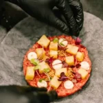 Chef finishing a steak tartare topped with apple, mustard seeds and microgreens at La Bodeguilla Palma