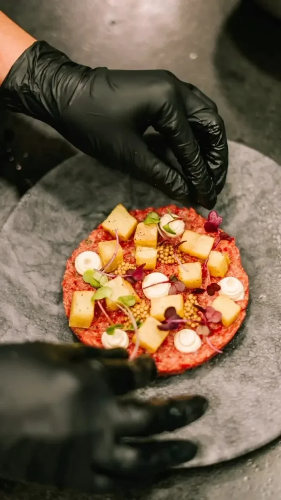 Chef finishing a steak tartare topped with apple, mustard seeds and microgreens at La Bodeguilla Palma