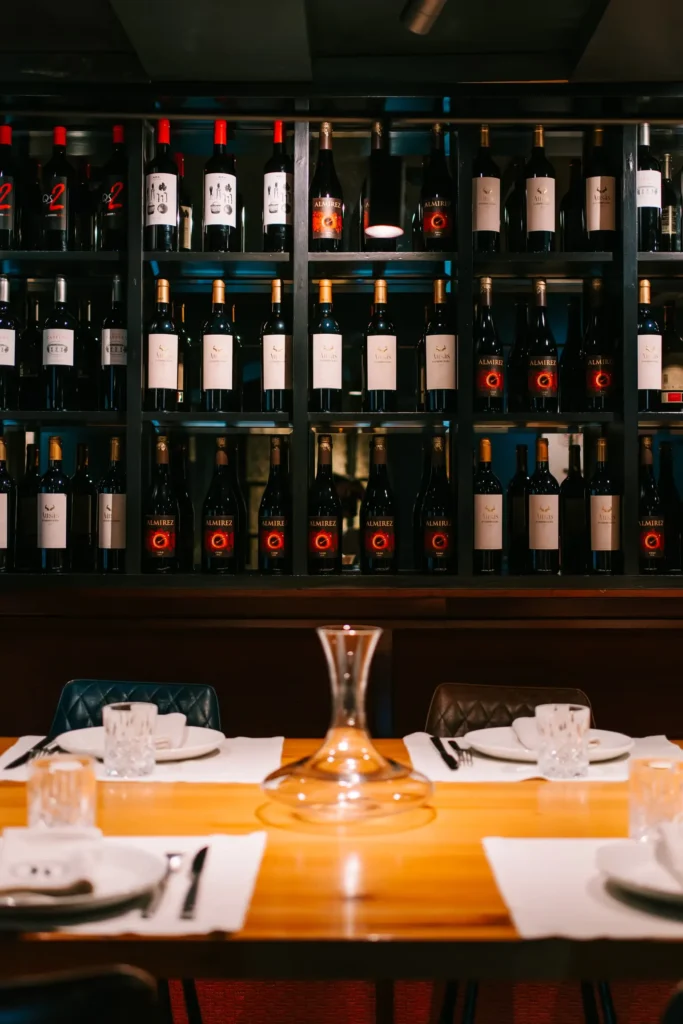 Table set with a decanter before a shelved red-wine wall at La Bodeguilla Palma