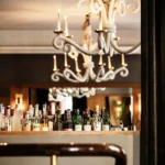 Bar lined with spirit bottles beneath a sculptural white chandelier at lavenue Paris