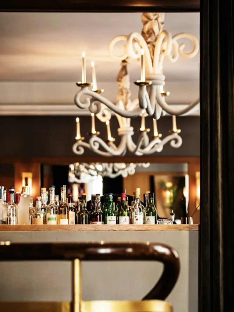 Bar lined with spirit bottles beneath a sculptural white chandelier at lavenue Paris