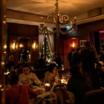 Busy candlelit dining room full of guests under a white chandelier at lavenue Paris