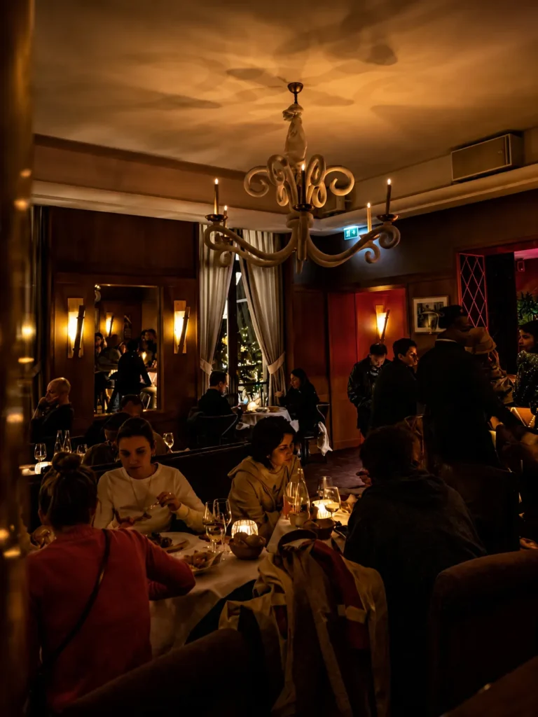 Busy candlelit dining room full of guests under a white chandelier at lavenue Paris
