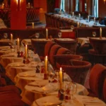 Rows of candlelit tables and plush velvet chairs in the warm-lit dining room at lavenue Paris