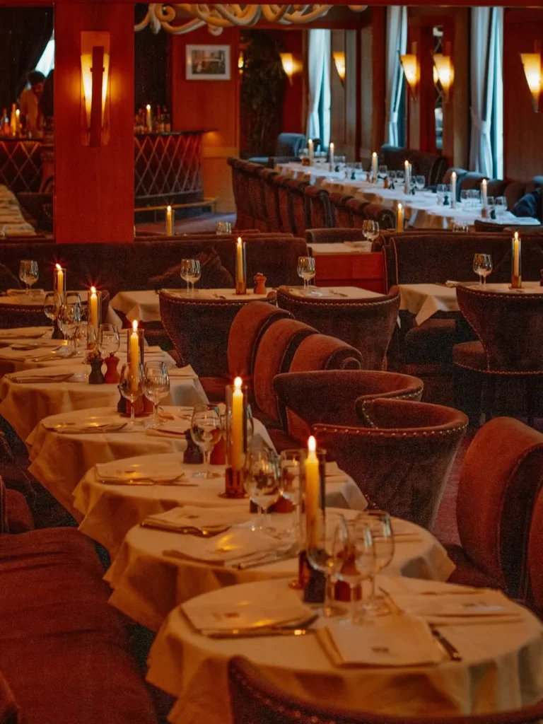 Rows of candlelit tables and plush velvet chairs in the warm-lit dining room at lavenue Paris