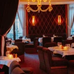 Dining room with a studded burgundy wall, sculptural white chandelier and dark velvet armchairs at lavenue Paris