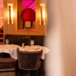 Velvet banquette table below a ball of red roses framed by alabaster sconces at lavenue Paris