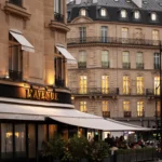 Gold lavenue sign above the awning and hedged terrace on Avenue Montaigne at dusk at lavenue Paris