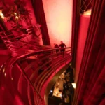 Curved staircase bathed in red light above the dining room at lavenue Paris