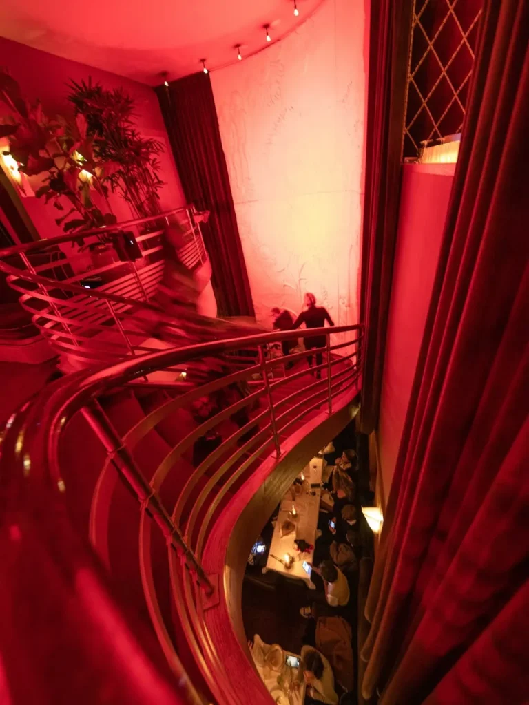 Curved staircase bathed in red light above the dining room at lavenue Paris