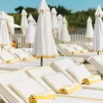Rows of white sunbeds with yellow-trimmed towels and folded parasols at Loulou Restaurant Saint-Tropez