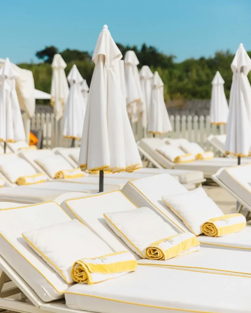Rows of white sunbeds with yellow-trimmed towels and folded parasols at Loulou Restaurant Saint-Tropez