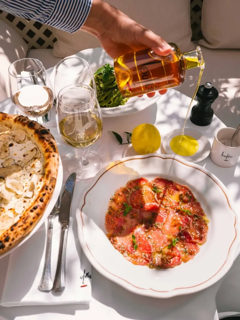 Beef carpaccio and a truffle pizza with olive oil poured over pasta at Loulou Restaurant Saint-Tropez