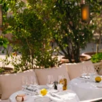 Set tables and banquettes among lanterns and greenery at Loulou Restaurant Saint-Tropez