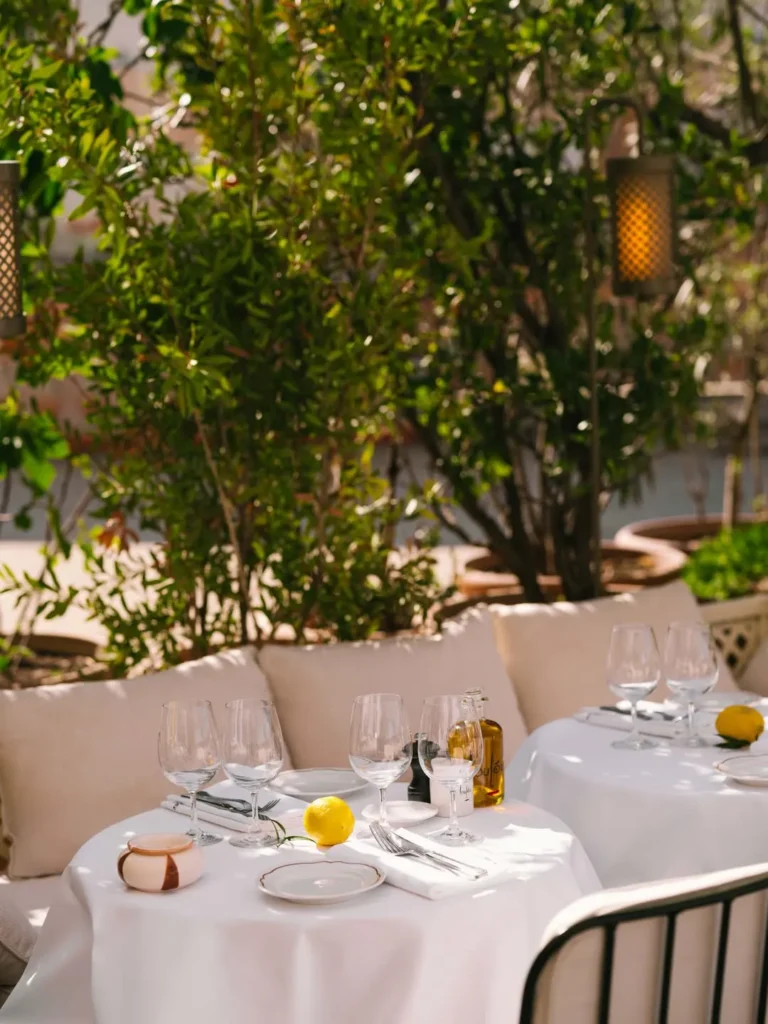 Set tables and banquettes among lanterns and greenery at Loulou Restaurant Saint-Tropez