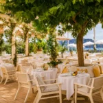 Dining room under a vine-covered pergola around a central tree with a sea view at Loulou Restaurant Saint-Tropez