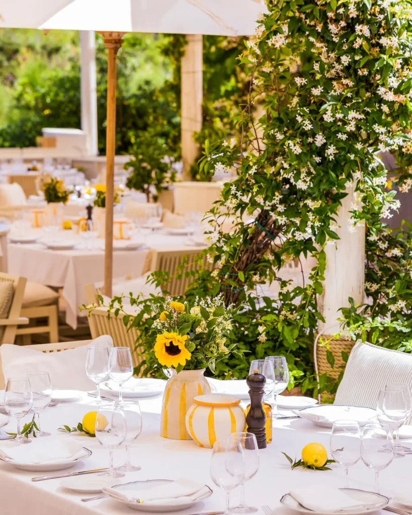 Table dressed with sunflowers and lemons beside flowering jasmine at Loulou Restaurant Saint-Tropez